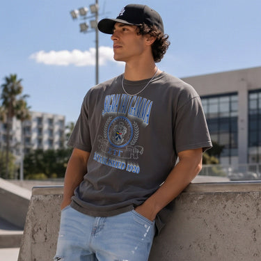 College-aged male wearing the fraternity Collegiate Crest Graphic Tee in charcoal grey, featuring vintage Sigma Tau Gamma crest artwork on campus.
