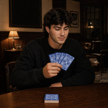 Fraternity brother holding custom Heritage Playing Cards during a poker game in a chapter house lounge.